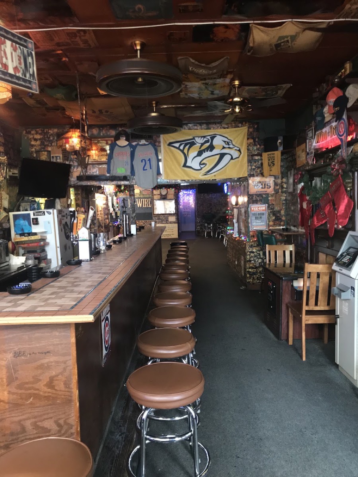 Inside The Villager Tavern's dart room and bar, with a Nashville Predators flag, bar stools, and decades of memorabilia on the walls
